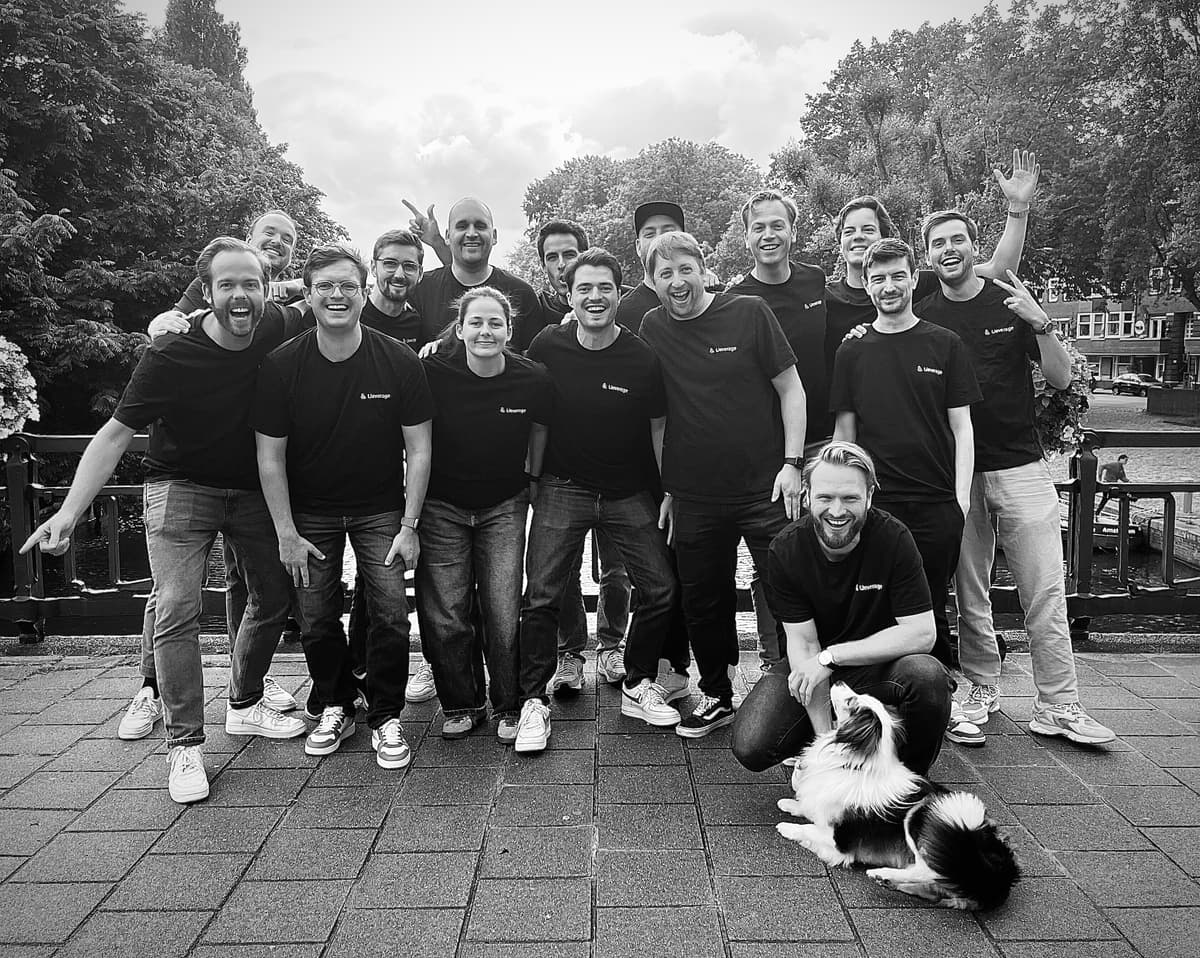 The Lleverage team in branded T-shirts, gathered on an Amsterdam canal bridge with a dog